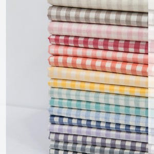 May include: A stack of 14 gingham fabric swatches in various colors, including beige, pink, red, orange, yellow, blue, and purple.
