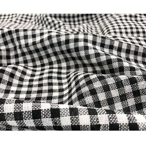 May include: Black and white gingham fabric with a woven texture. The fabric is folded and has a slight crinkle.