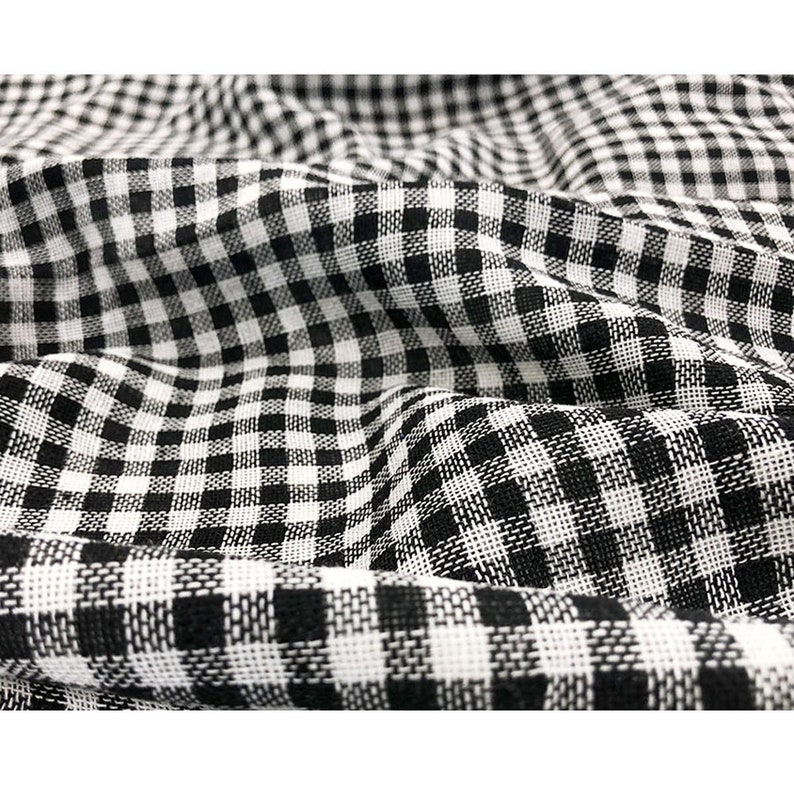 May include: Black and white gingham fabric with a woven texture. The fabric is folded and has a slight crinkle.