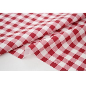 May include: Red and white checkered fabric with a water-resistant coating. The fabric is folded in half, showing the water droplets on the surface.