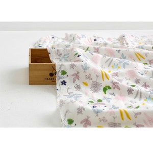 May include: White cotton fabric with a colorful floral print featuring small green, pink, and yellow flowers, leaves, and vines. The fabric has a subtle texture and a soft, lightweight feel.