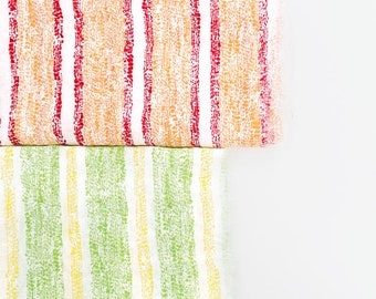 May include: Two fabric swatches with a white background and colorful stripes. The top swatch has red, orange, and yellow stripes. The bottom swatch has green and yellow stripes.