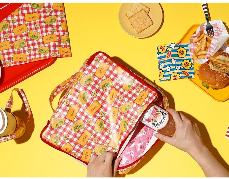 May include: A picnic-themed set featuring a red and white checkered lunch bag with a butter pattern, a red tray, and a small basket. The scene includes a burger, fries, crackers, and a jar of jam, all set against a yellow background.