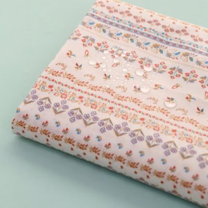 May include: White fabric with a repeating pattern of small flowers and geometric shapes in shades of pink, orange, and blue. The fabric is water-resistant and has water droplets on the surface.
