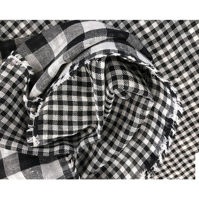 May include: Black and white gingham fabric with a frayed edge. The fabric is folded and textured.