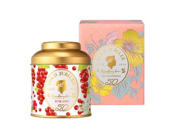 May include: A gold-lidded tin and a pink box with floral designs. The tin features red berries and the words "GOLD JUBILEE" and "50th Anniversary." The box has a similar design with the same text. The products are likely tea or a similar product.