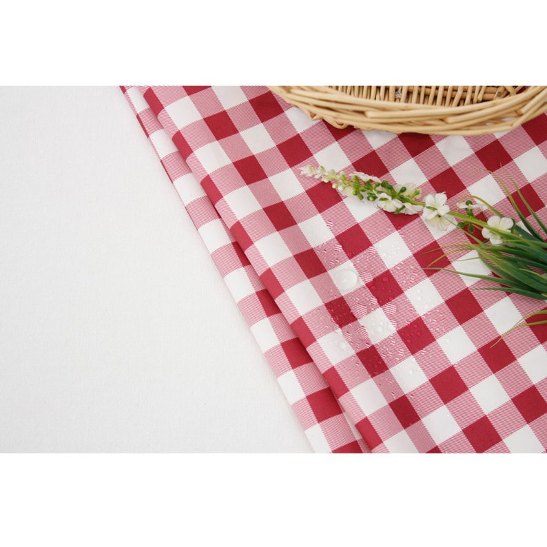 May include: Red and white checkered tablecloth with water droplets on the surface. A wicker basket and white flowers are visible in the background.