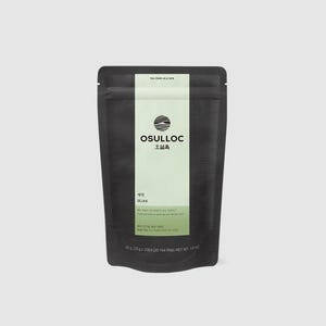 May include: A black tea bag package with a vertical light green stripe down the center. The package features the brand name "OSULLOC" in white and Korean characters, along with the tea type "SEJAK". The package also includes text about the tea's ingredients.