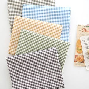 May include: Five different fabric swatches with a gingham pattern. The swatches are in brown, light blue, yellow, green, and black.