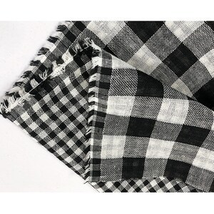 May include: Black and white checkered fabric with a frayed edge. The fabric is folded in half, revealing a second layer of checkered fabric.