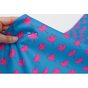 May include: Blue fabric with a repeating pattern of pink tulips. The fabric is 2 cm wide.