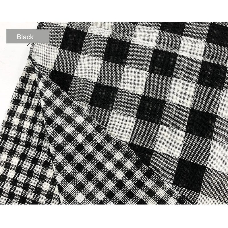 May include: Black and white checkered fabric with a larger checkered pattern on top. The fabric is woven and has a slightly textured surface.