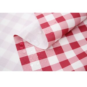 May include: Red and white checkered fabric with water droplets on the surface. The fabric is waterproof and is ideal for outdoor use.