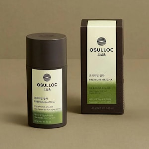 May include: A brown cylindrical container with a green label that reads "OSULLOC" and "Premium Matcha". The label also includes the text "Deep Flavored First-flush Organic Matcha" and "Tea powder Green Tea 100%". The container is 40g (1.41 oz).
