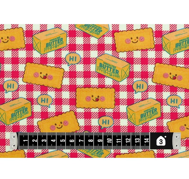 May include: Fabric with a repeating pattern of smiling cartoon crackers, butter boxes, and speech bubbles with "HI" on a red and white checkered background. A measuring tape shows 3 inches.