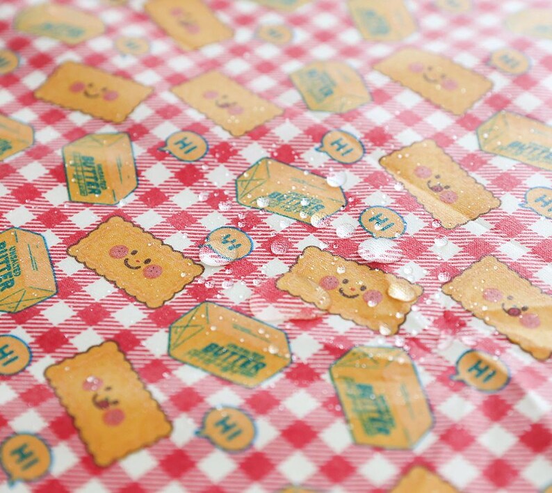 May include: A red and white checkered pattern with repeating illustrations of smiling crackers, butter cartons, and speech bubbles with the word "Hi". The design has a playful, cartoonish style.
