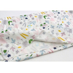 May include: White fabric with a repeating pattern of small green, blue, pink, and yellow floral and animal illustrations. The fabric is folded in half, showing the back side.