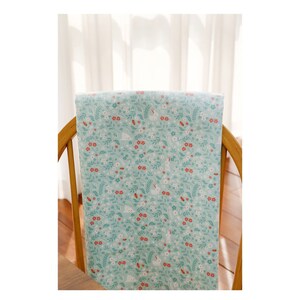 May include: A light blue fabric with a white bunny and floral pattern. The fabric is draped over a wooden chair.