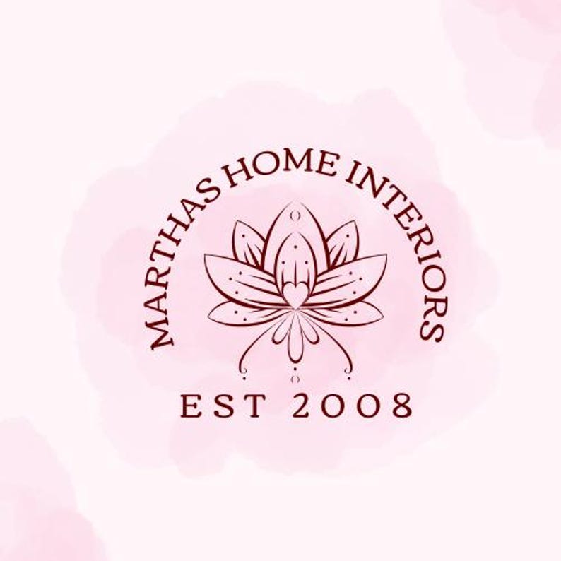 May include: A logo for "MARTHAS HOME INTERIORS" with a dark red-brown lotus flower design at its centre. The text is arranged in a semi-circle around the flower, with "EST 2008" below. The background has a soft pink watercolour effect.