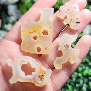 May include: Four white agate stone carvings of various animal shapes. The carvings have holes and a translucent, milky white color with yellow and brown inclusions.