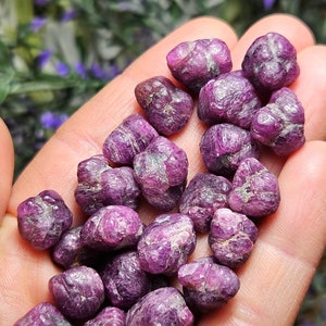 Peut inclure: Une collection de petites pierres précieuses de couleur violette, taillées grossièrement. Les pierres sont de différentes nuances de violet et ont un aspect naturel et non poli.