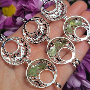 May include: Four silver locket pendants with intricate filigree designs. Each locket features a crescent moon shape with a clear window revealing green crystals inside.