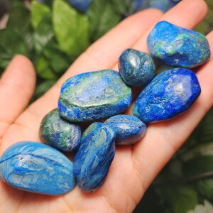 May include: A handful of polished azurite stones, showcasing a vibrant mix of deep blue and green hues. The stones vary in size and shape, with a smooth, rounded texture. The natural color variations create a striking visual appeal, perfect for collectors or crystal enthusiasts.
