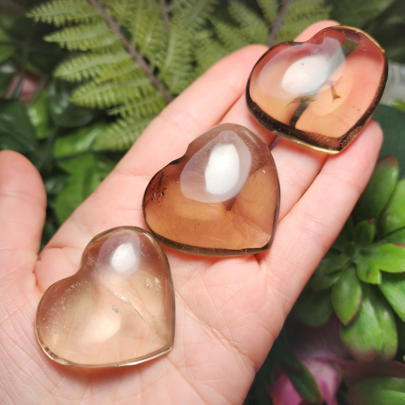 Puede incluir: Tres cristales de cuarzo ahumado en forma de coraz&oacute;n. Los cristales son transl&uacute;cidos y tienen un color marr&oacute;n claro.