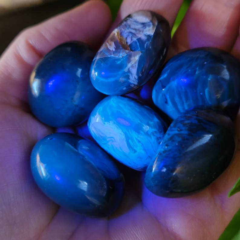 May include: A collection of six blue and white tumbled stones. The stones are smooth and polished, and they have a variety of patterns and textures.