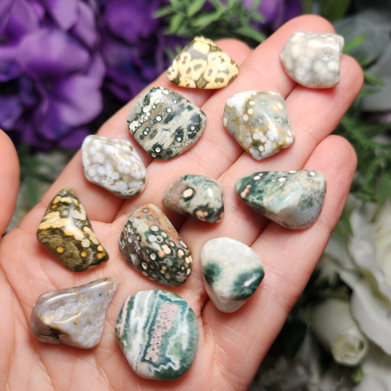 May include: A collection of 10 ocean jasper tumbled stones in various shades of green, brown, white, and gray with unique patterns.