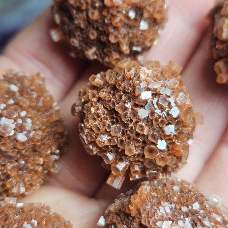 May include: Close-up of several brown, crystal-like formations. The crystals are clustered together in a rounded shape, resembling small, spiky balls.