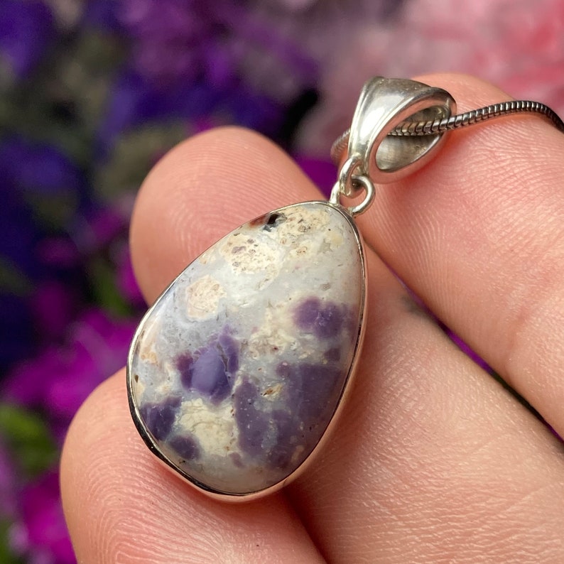 May include: A silver pendant with a teardrop-shaped purple and white opal stone.