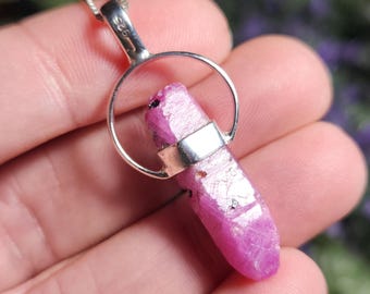 May include: A pink ruby crystal pendant set in a sterling silver bezel and ring. The pendant is approximately 1 inch long.