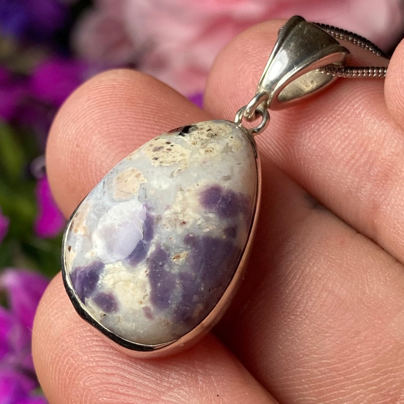 May include: A silver pendant with a teardrop-shaped purple and white opal stone.