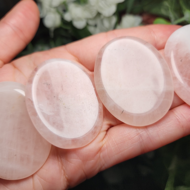 May include: Three smooth, white, oval-shaped polished stones. The stones are translucent and have a slight pink hue.