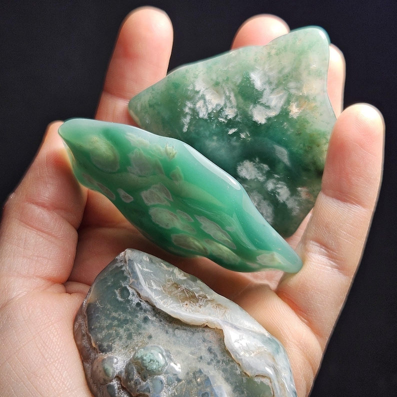 May include: Three green and white agate stones with a mottled pattern. The stones are smooth and polished.