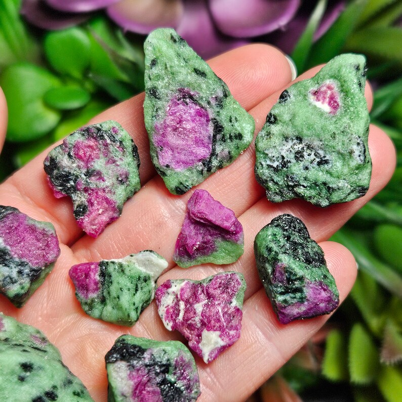 Pu&ograve; includere: Una collezione di pietre grezze di rubino in zoisite. Le pietre presentano un mix di tonalit&agrave; verdi, nere e rosa. Il rubino rosa &egrave; incastonato nella zoisite verde, creando un contrasto sorprendente. Le pietre variano per dimensioni e forma.