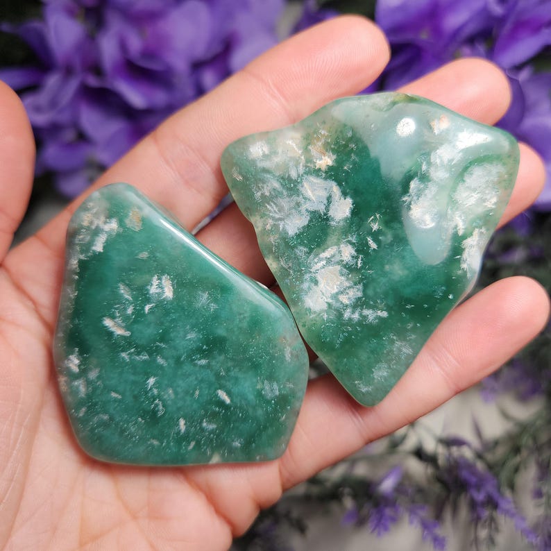 May include: Two green and white agate tumbled stones with a smooth, polished finish. The stones have a unique pattern of white inclusions.
