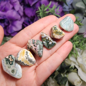 May include: A collection of six polished ocean jasper stones in various shades of green, brown, white, and pink. The stones are smooth and have a unique, swirling pattern.