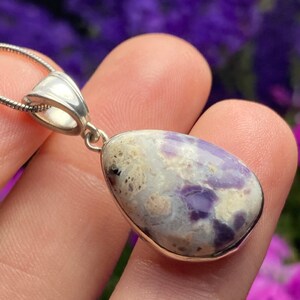 May include: A teardrop-shaped pendant with a silver bail and a white and purple opal stone.
