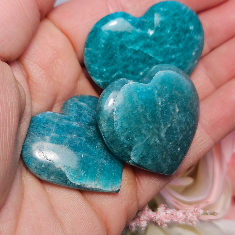 Peut inclure: Trois pierres d'amazonite en forme de c&oelig;ur de couleur vert turquoise. Les pierres sont lisses et polies, avec une texture naturelle et organique.
