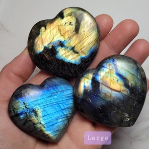 May include: Three labradorite heart-shaped crystals, one large and two smaller, with iridescent blue and gold colors.