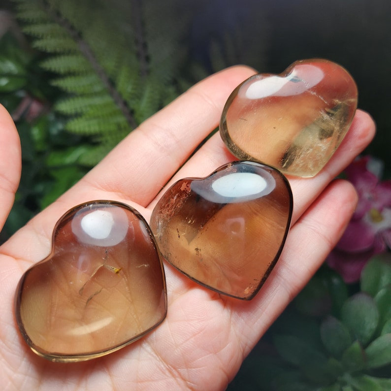 Puede incluir: Tres cristales de cuarzo ahumado en forma de coraz&oacute;n. Los cristales son transl&uacute;cidos y tienen un color marr&oacute;n claro.