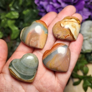 May include: Four heart-shaped polished stones with brown, white, and gray swirling patterns. The stones are smooth and have a natural, polished finish.