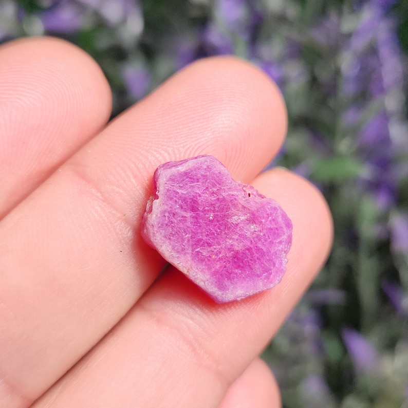 May include: A pink ruby crystal with a rough, faceted surface.