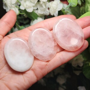 May include: Three smooth, oval-shaped rose quartz stones, polished to a high shine, with a pale pink color.