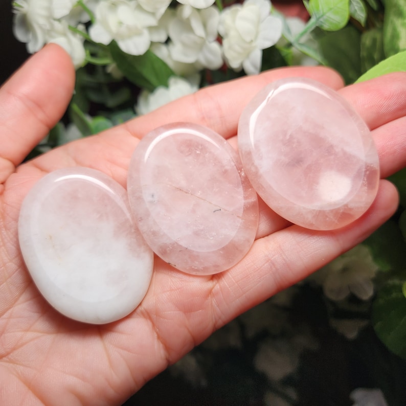 May include: Three smooth, oval-shaped rose quartz stones, polished to a high shine, with a pale pink color.