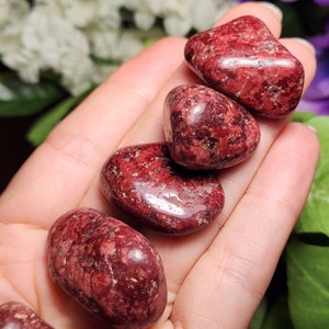 May include: Five tumbled red jasper stones with a speckled pattern. The stones are smooth and polished.