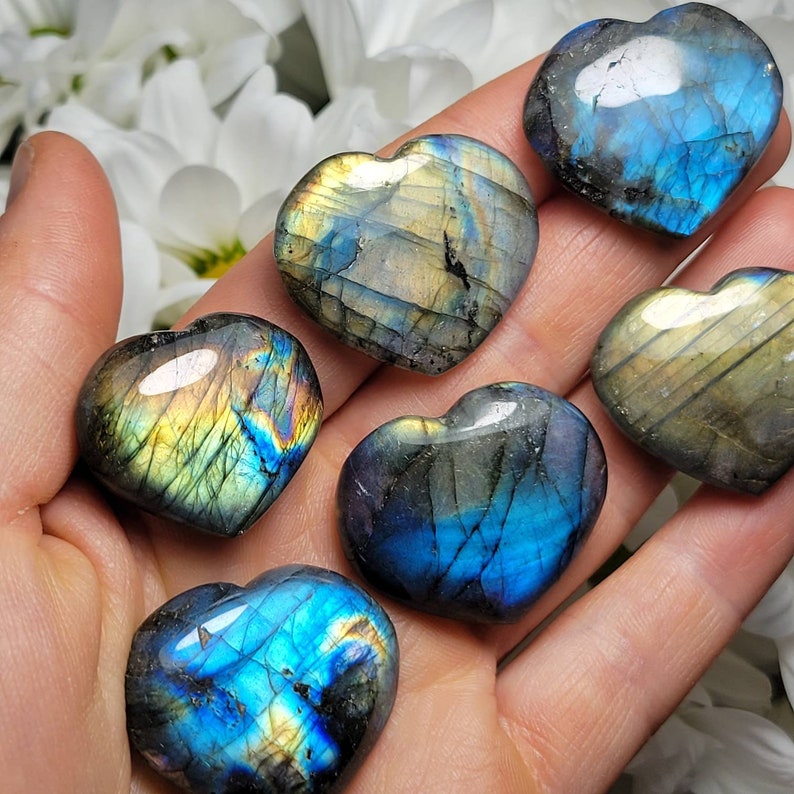 May include: Six heart-shaped labradorite crystals in various shades of blue, green, and gold. The crystals are polished and have a iridescent sheen.
