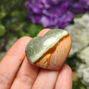 May include: A heart-shaped polished stone with brown, green, and white patterns.